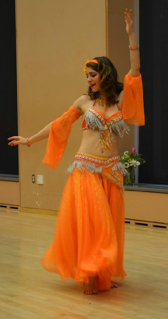 Photo of Carrie in orange belly dance costume.